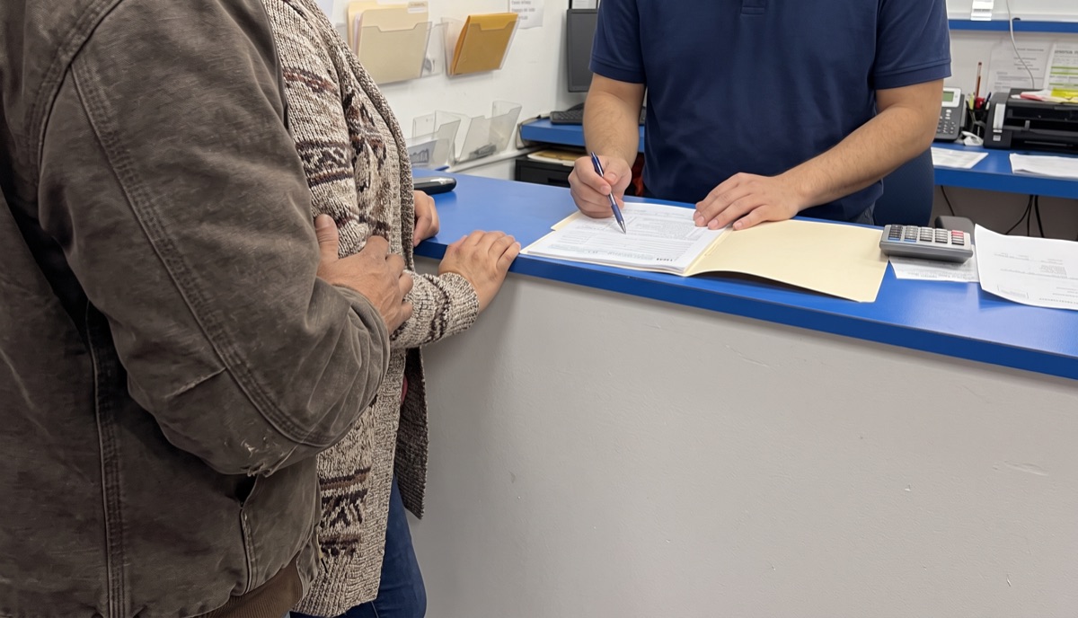 Una pareja frente al mostrador mientras les revisan los papeles de sus impuestos